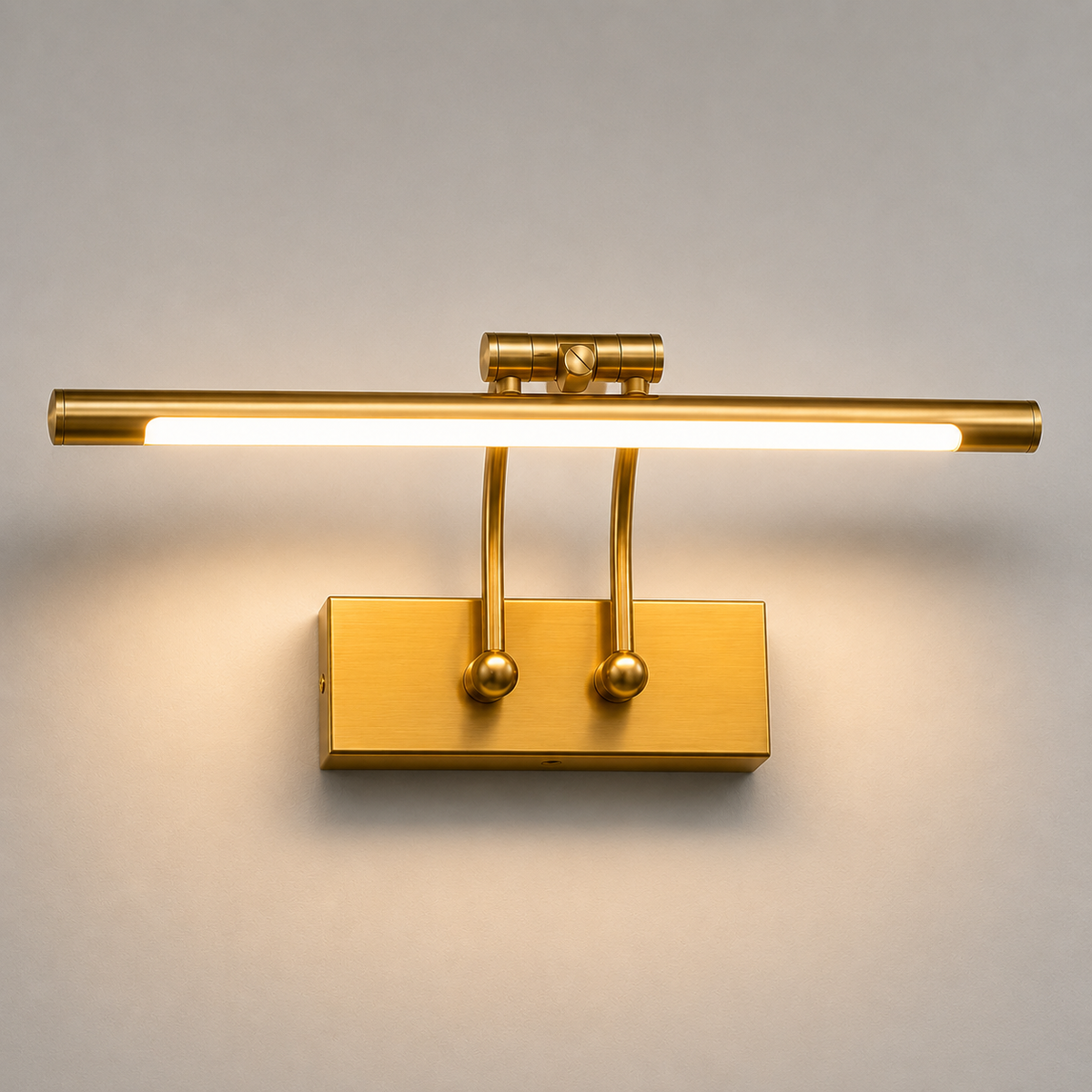 A modern wall-mounted reading light with a brushed gold finish, featuring a horizontal bar with a glowing LED light tube and two adjustable vertical arms on a rectangular base, shown against a neutral light gray background.