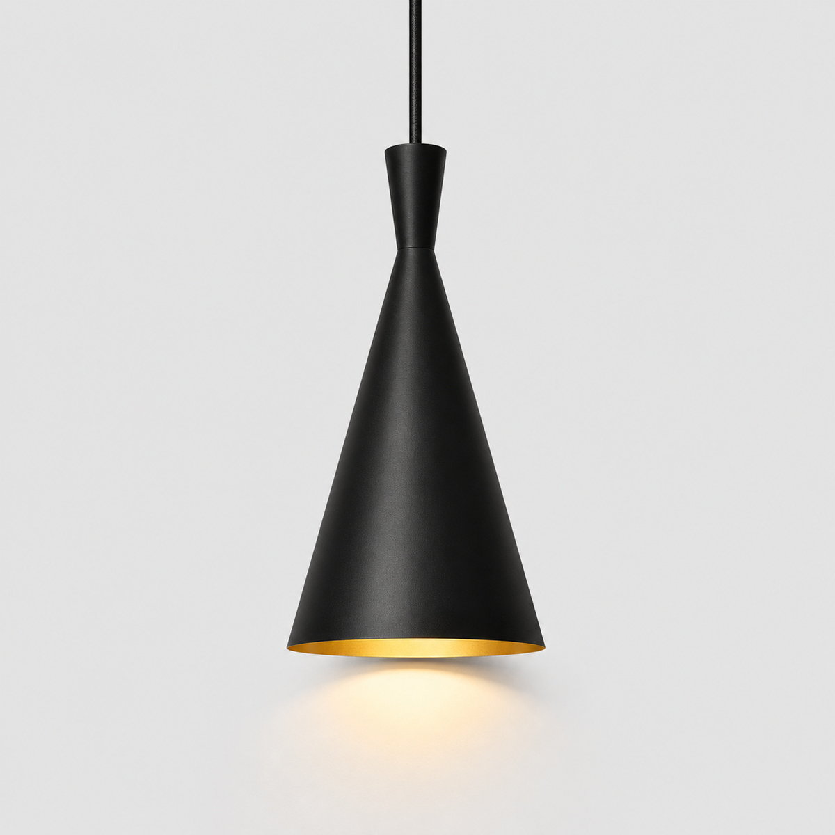 A modern black pendant light with a tapered cone-shaped shade and a gold interior, suspended by a black cord against a light gray background.