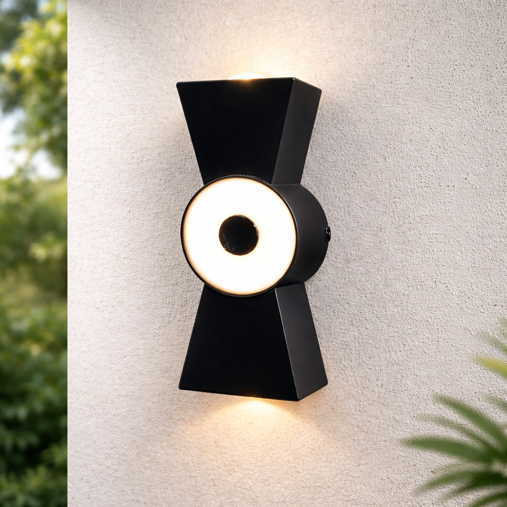 Modern black wall light fixture on a textured white wall with greenery around.