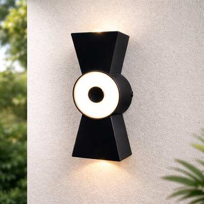 Modern black wall light fixture on a textured white wall with greenery around.