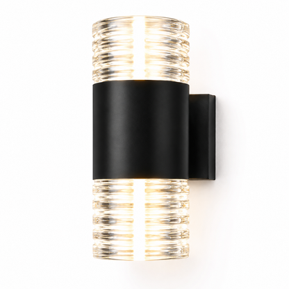 A modern wall-mounted light fixture with a matte black cylindrical band and clear ribbed glass top and bottom sections, shown lit against a plain white background.